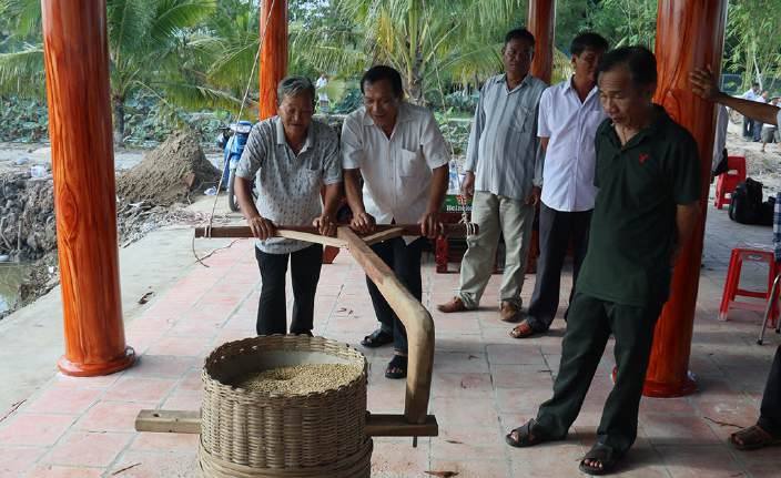 Trying a wooden rice pounder at a village house.