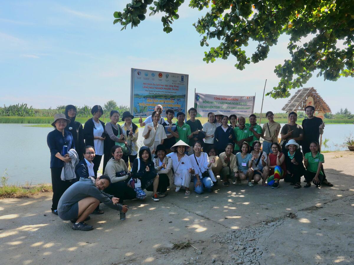 A group with their hosts on the riverbank in Cẩm Kim, Hội An.