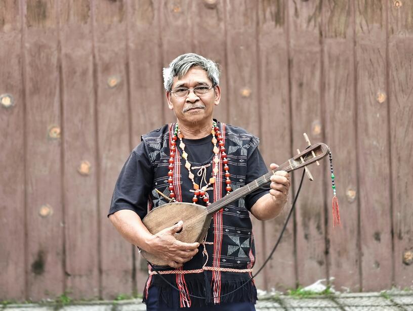 A Cơ Tu musician with a traditional string instrument.