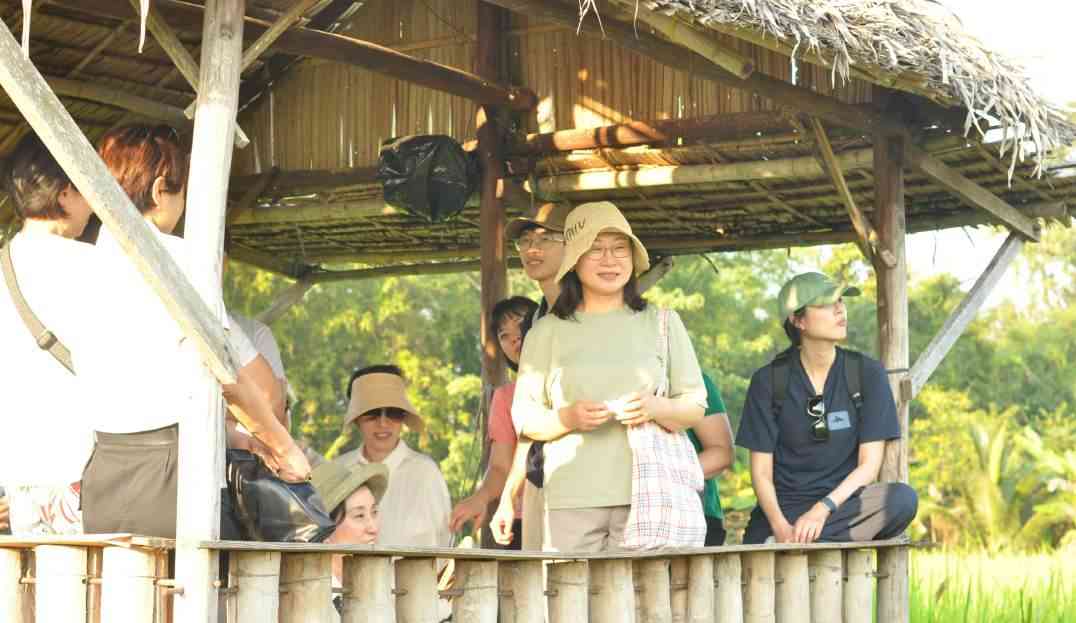 Travelers and hosts under a field shelter.